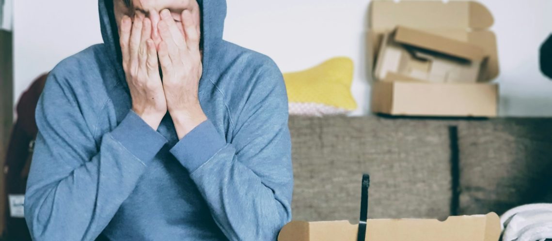 man covering face with both hands while sitting on bench